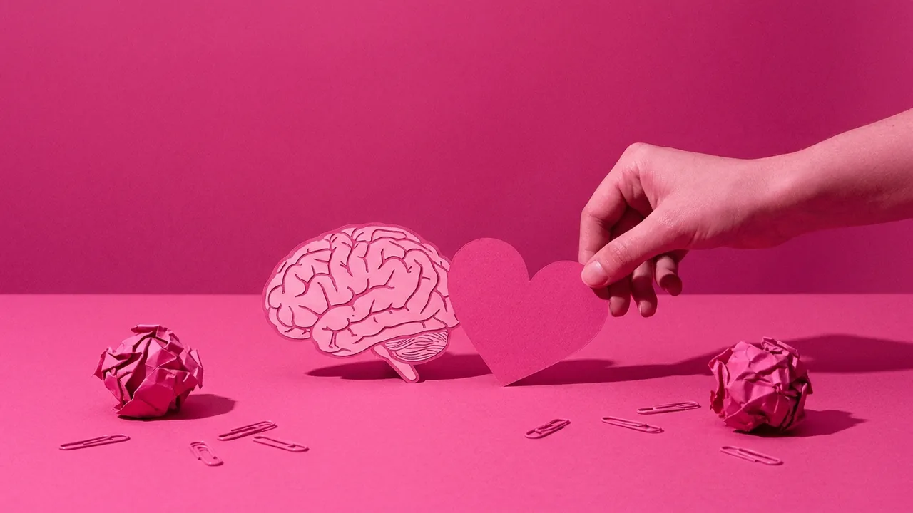 Bodegón en tonos rosa: recortes de un cerebro y un corazón sobre la mesa, metáfora de top of mind frente a top of heart